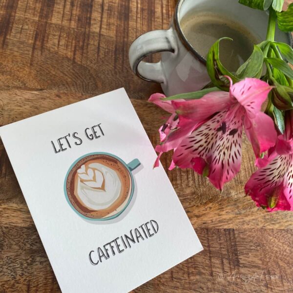 Mood image of an original AmuzAnt greeting card with the text "Let's Get Caffeinated and a coffee illustration.
